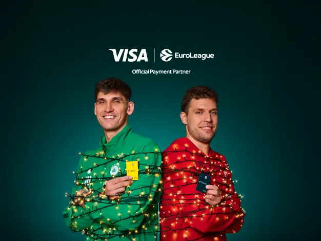 Δύο αθλητές να ποζάρουν με στολές και φωτάκια Χριστουγέννων τυλιγμένα γύρω τους. Ο ένας φοράει πράσινη στολή και κρατάει μια κάρτα Visa, ενώ ο άλλος φοράει κόκκινη στολή και κρατάει επίσης μια κάρτα Visa. Στο επάνω μέρος της εικόνας φαίνεται το λογότυπο της Visa και της EuroLeague, με την ένδειξη "Official Payment Partner".